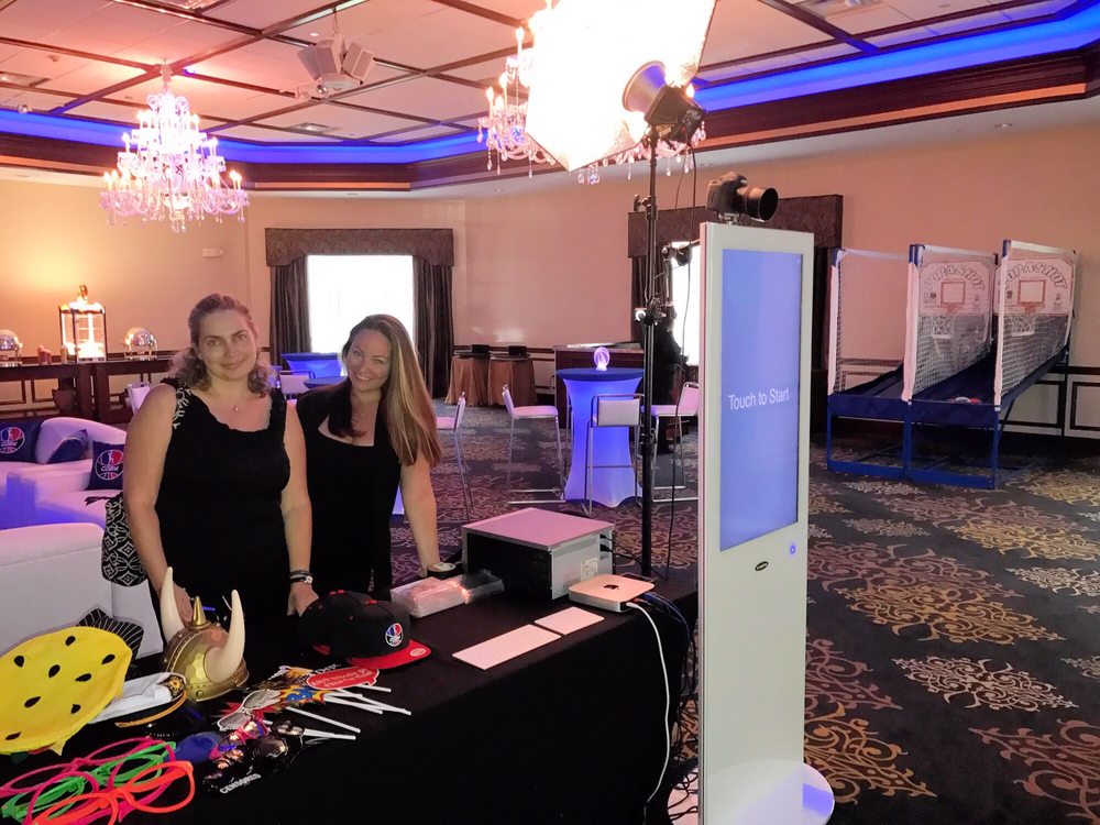 Touch-screen selfie booth and pop-a-shot arcade games set up in a ballroom